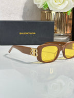 Sunglasses with brown frames and yellow lenses, gold logo detail on temples