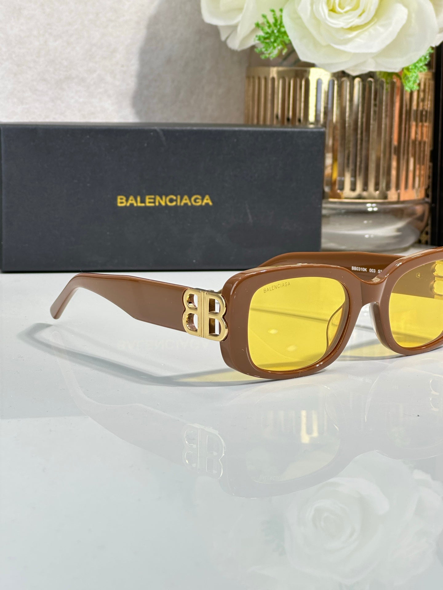 Sunglasses with brown frames and yellow lenses, gold logo detail on temples