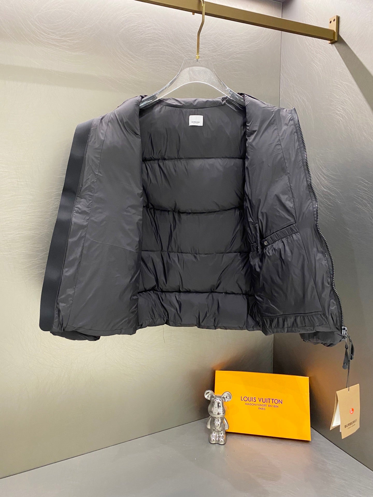 Hooded puffer jacket front view on hanger, dark gray quilted lining and full-zip.