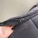 Puffer jacket zipper close-up with dark gray tape and metal pull, quilted fabric panel.