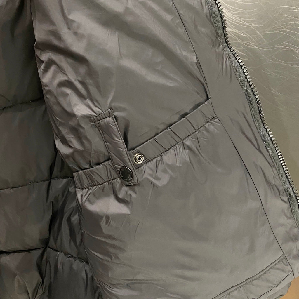 Puffer jacket inner lining close-up with snap button and stitched pocket seam.