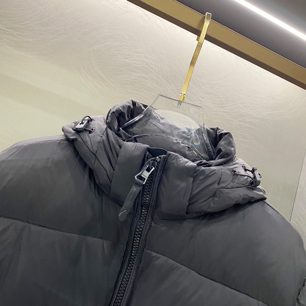 Hooded puffer jacket close-up of zipper and hood, dark gray quilted shell and pockets.