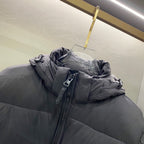 Hooded puffer jacket close-up of zipper and hood, dark gray quilted shell and pockets.