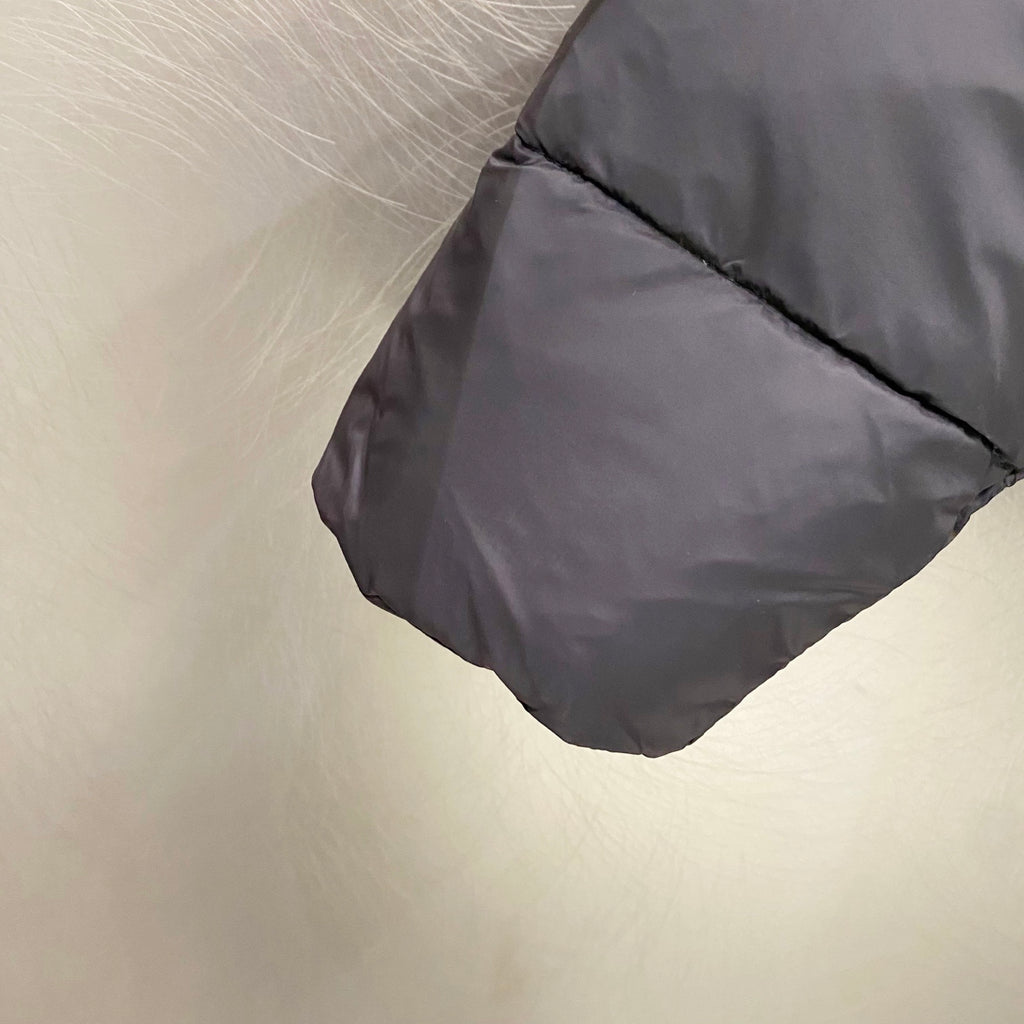Puffer jacket sleeve cuff detail with dark gray fabric and stitched hem fold.