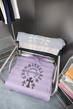 Folded lavender short-sleeve T-shirts with dark cross emblem and text print