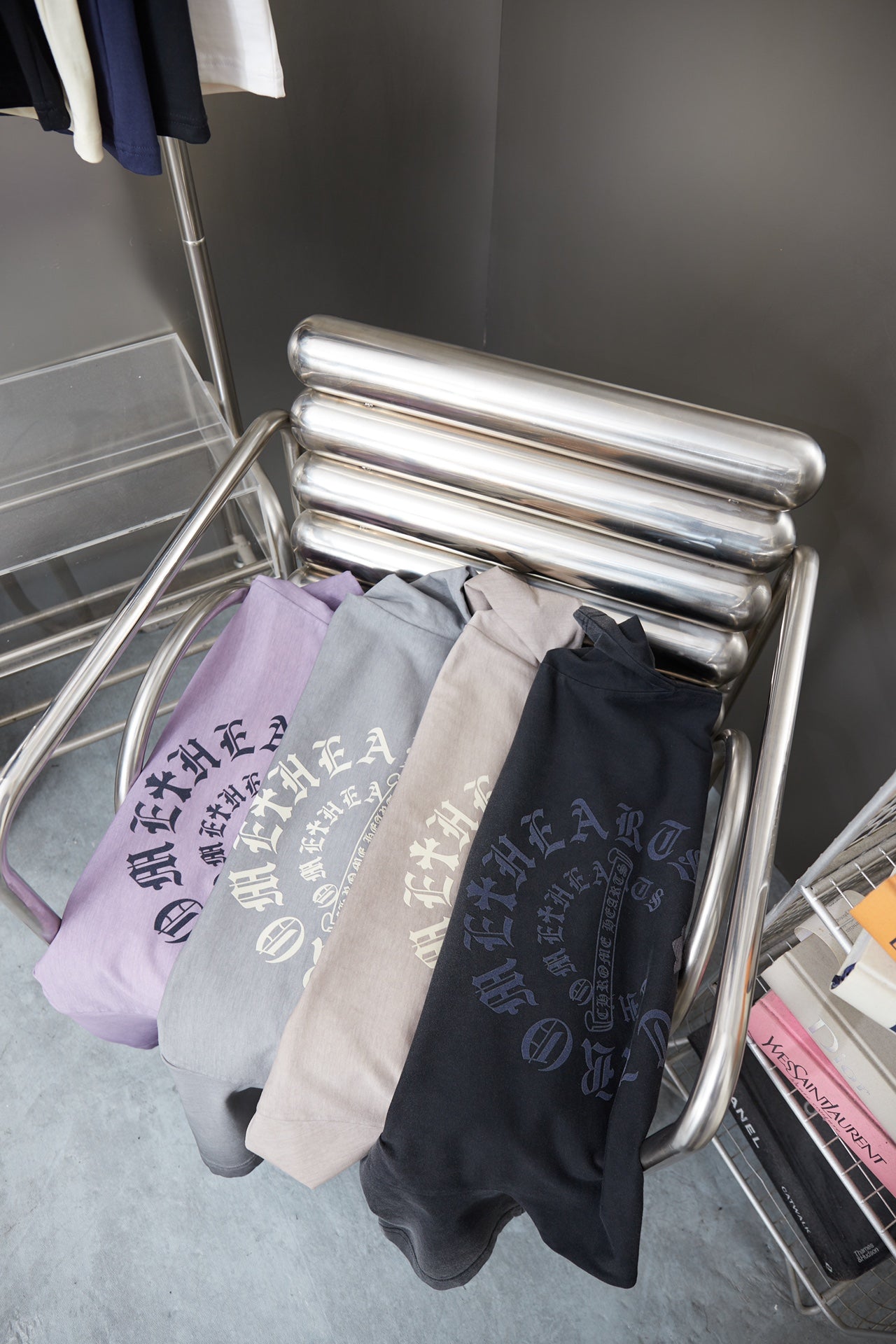 Stack of lavender and dark graphic drawstring shirts with runic-style print