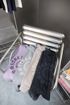 Folded T-shirts in light purple, gray, and black hanging on chrome rack