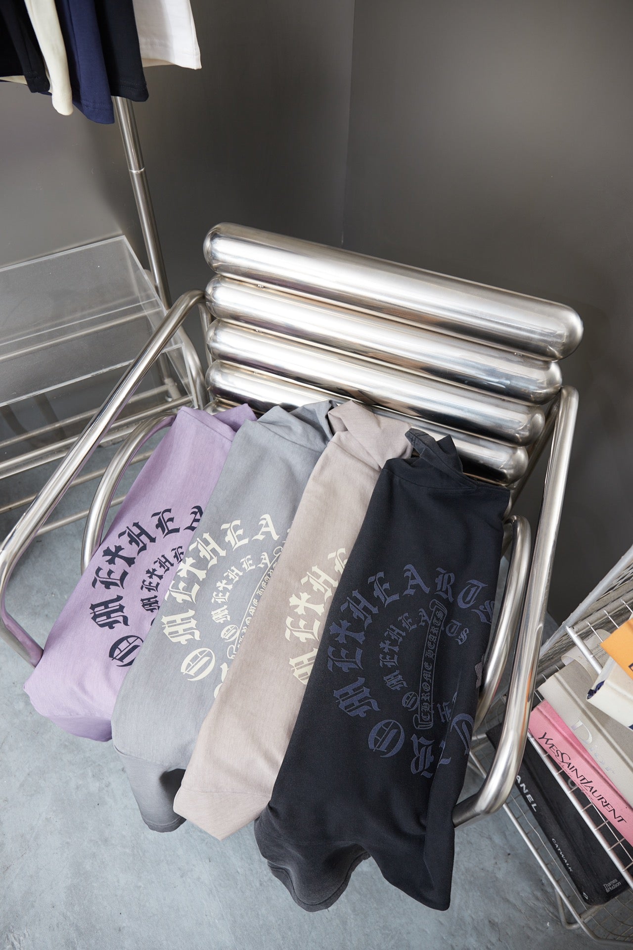 Stack of folded T-shirts in dark gray and light gray with cross-text print.