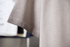 Light gray T-shirt with visible stitched side seam and curved hem.