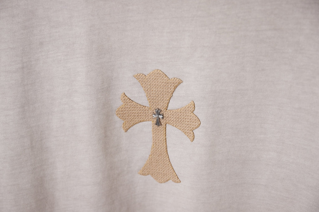 Light gray T-shirt with embroidered beige cross emblem detail.