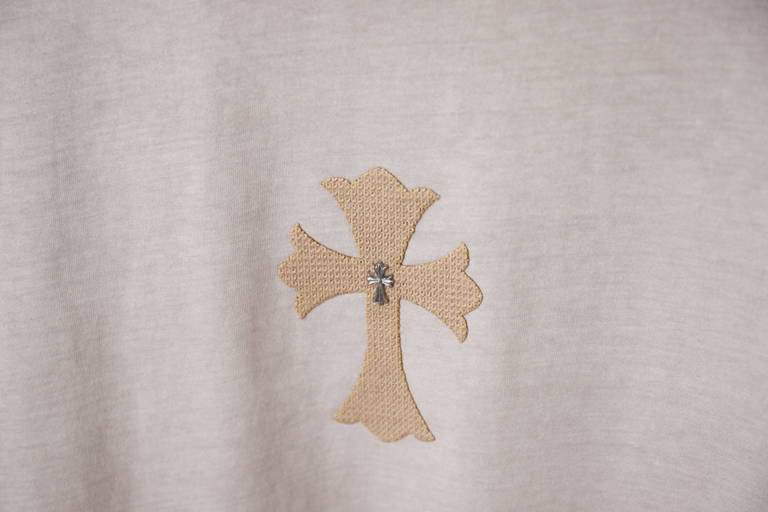 Light gray T-shirt with embroidered beige cross emblem detail.