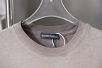Light gray T-shirt close-up with round ribbed collar and neck tag.