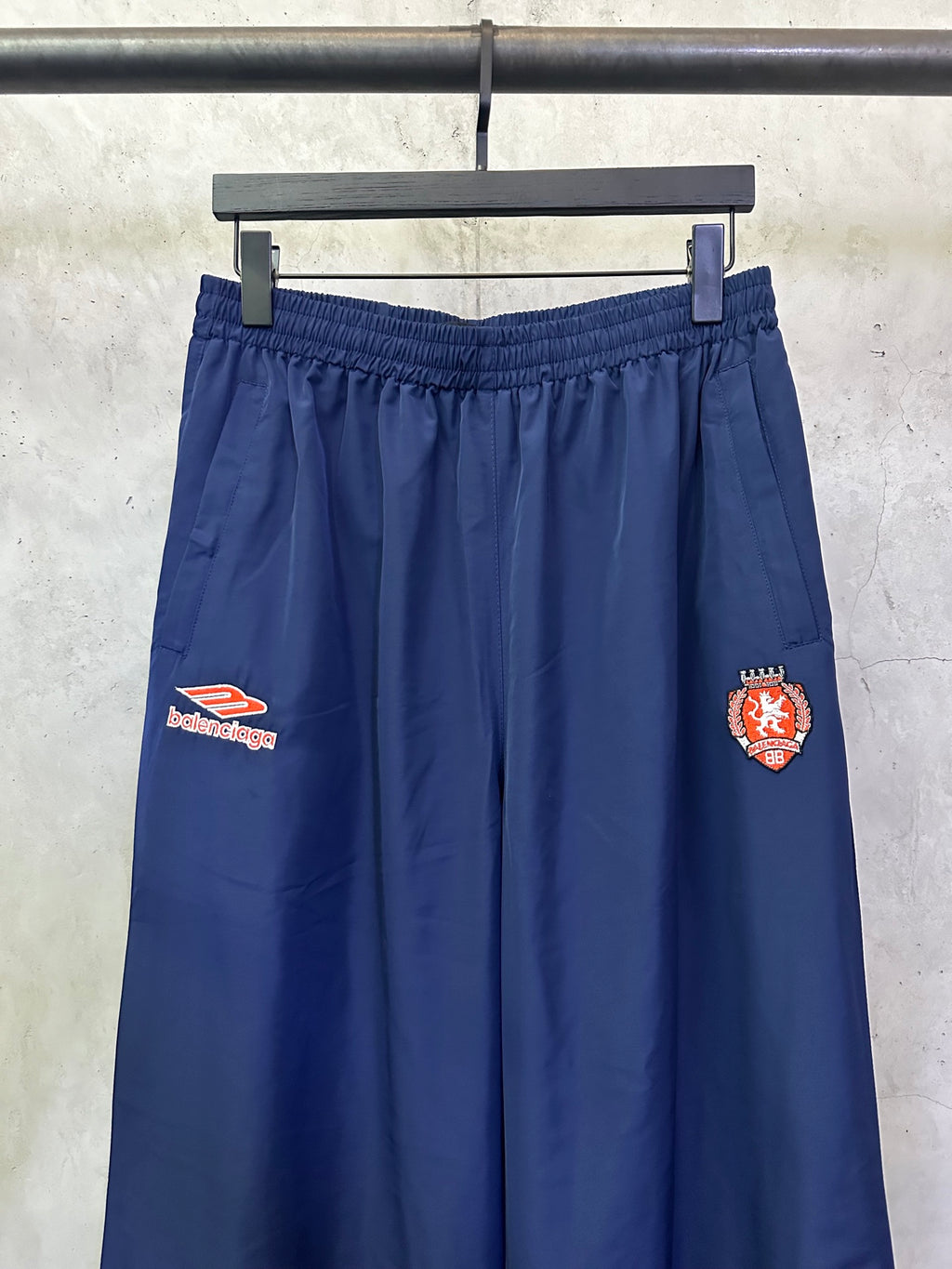 Blue wide-leg drawstring pants with embroidered crest patches on legs