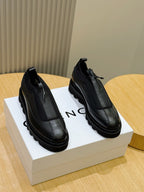 Lace-up leather shoes with dark black uppers and chunky rubber sole, side view