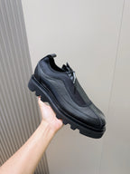 Lace-up leather shoe held in hand, dark textured upper with chunky sole and lace ties