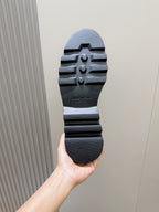 Shoe outsole with tread pattern and brand mark, held up for view