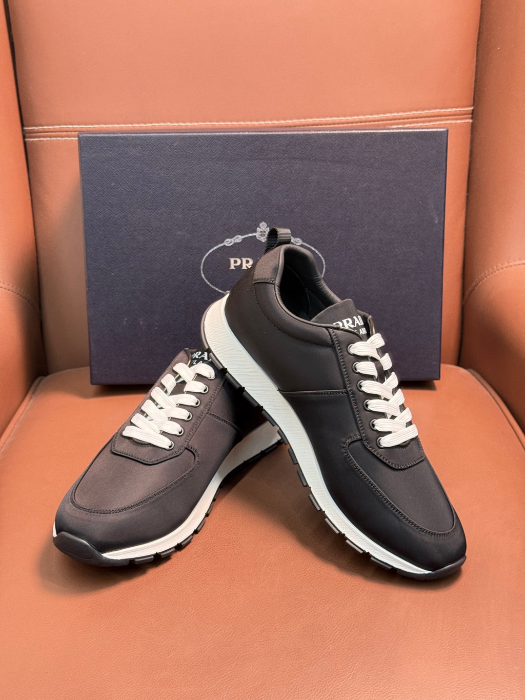 Black Prada sneakers on box, lace-up low tops with white laces and white edge sole