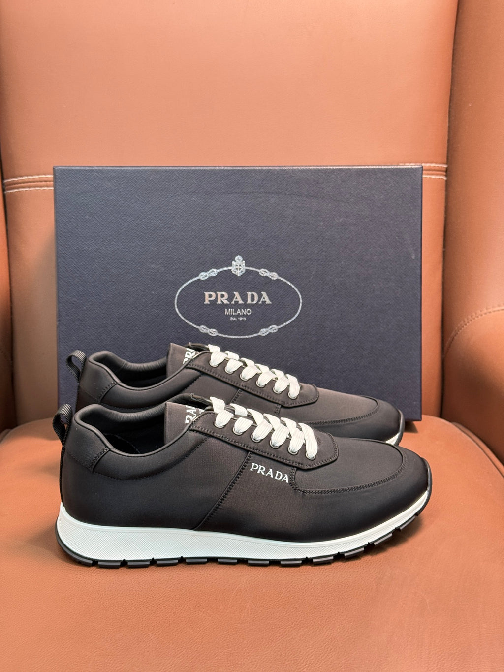 Black Prada sneakers on box, lace-up with white laces and contrasting white sole