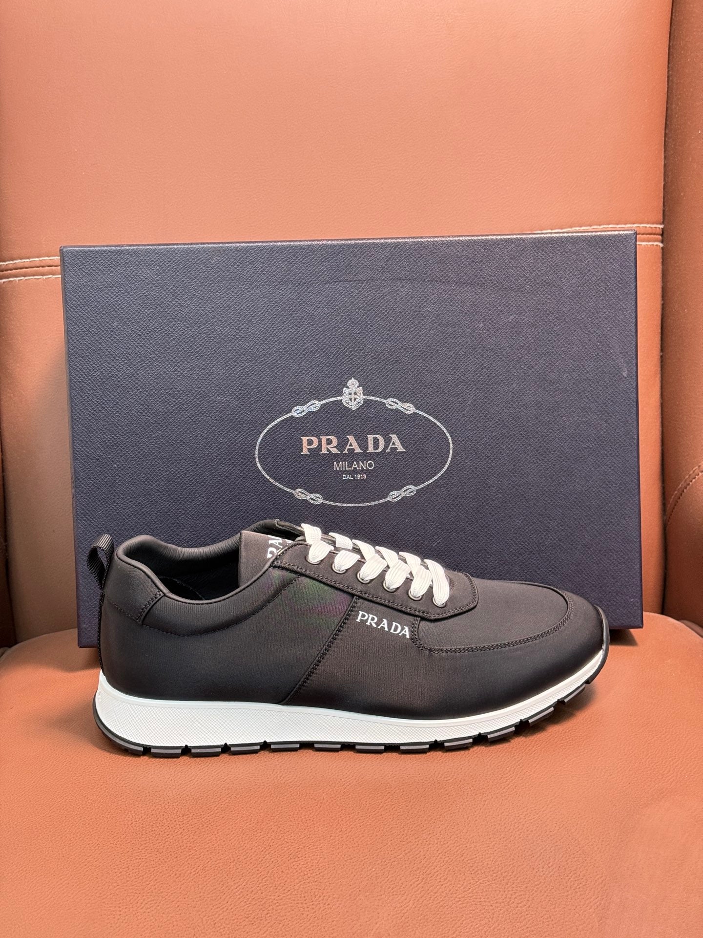 Black Prada sneakers on box, low-top lace-up with white laces and white rubber sole