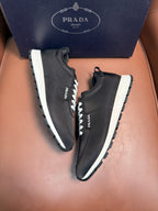 Black Prada sneakers, front three-quarter view, lace-up with white laces and thick sole