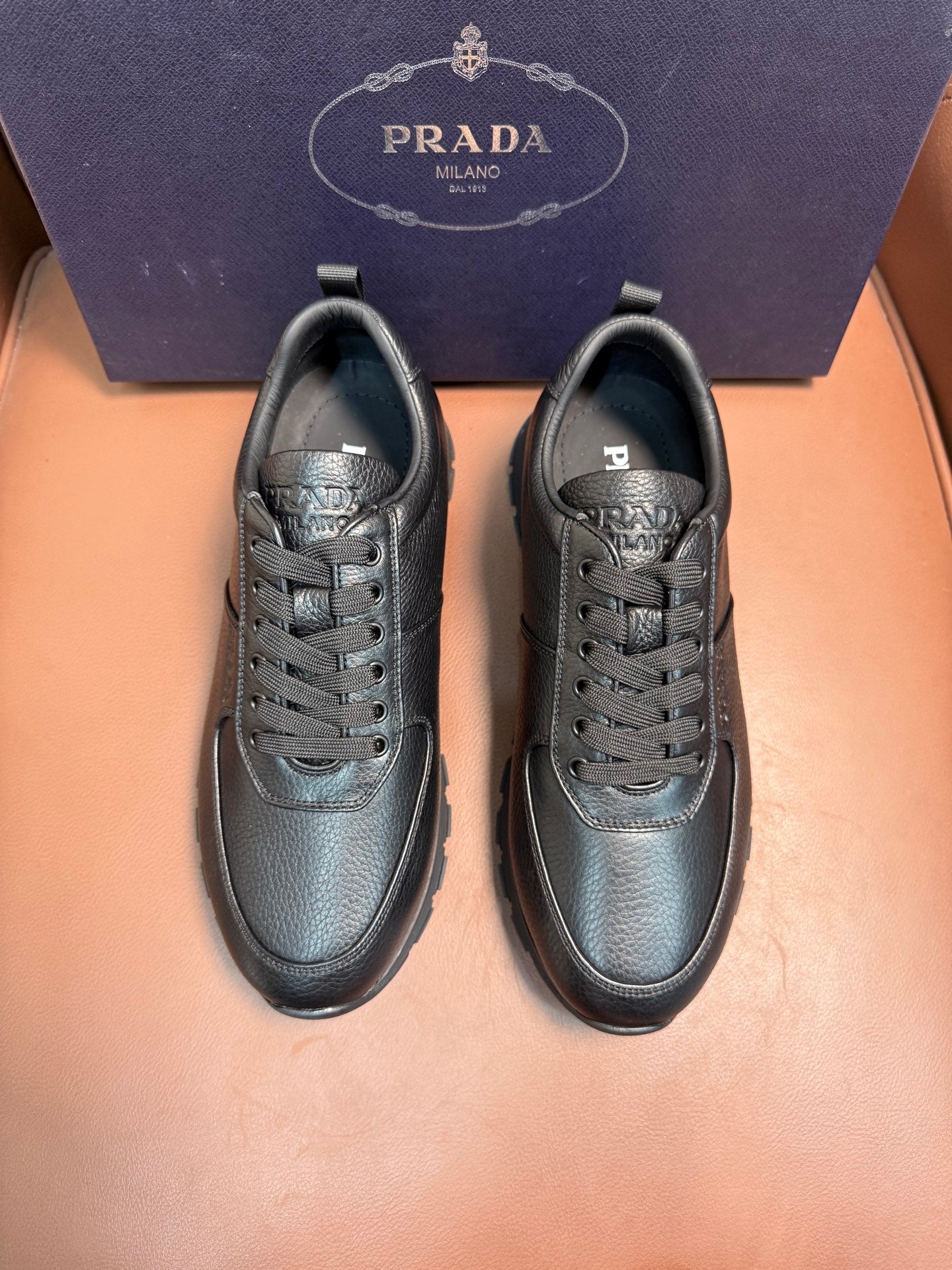 Pair of dark leather lace-up sneakers with rounded toe and low-profile sole