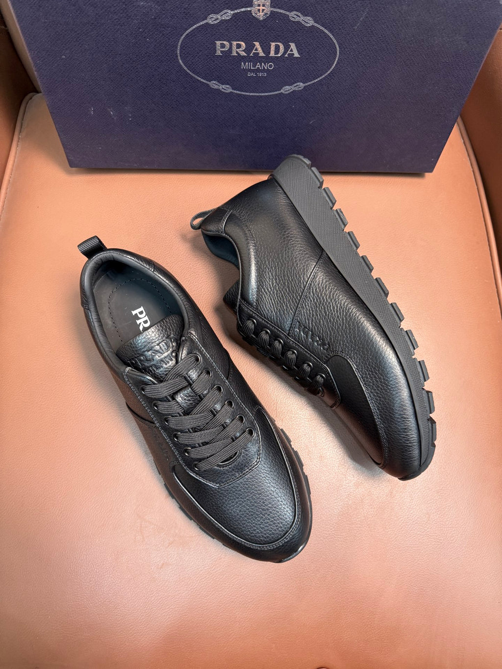 Dark leather lace-up sneakers, side view pair with stitched panels and tread sole