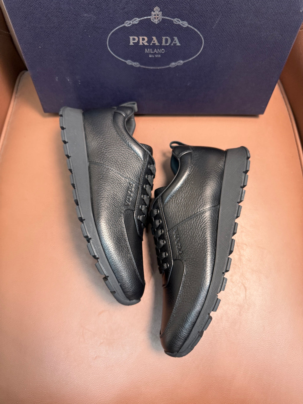 Dark leather lace-up sneakers, angled pair showing lace eyelets and rugged sole