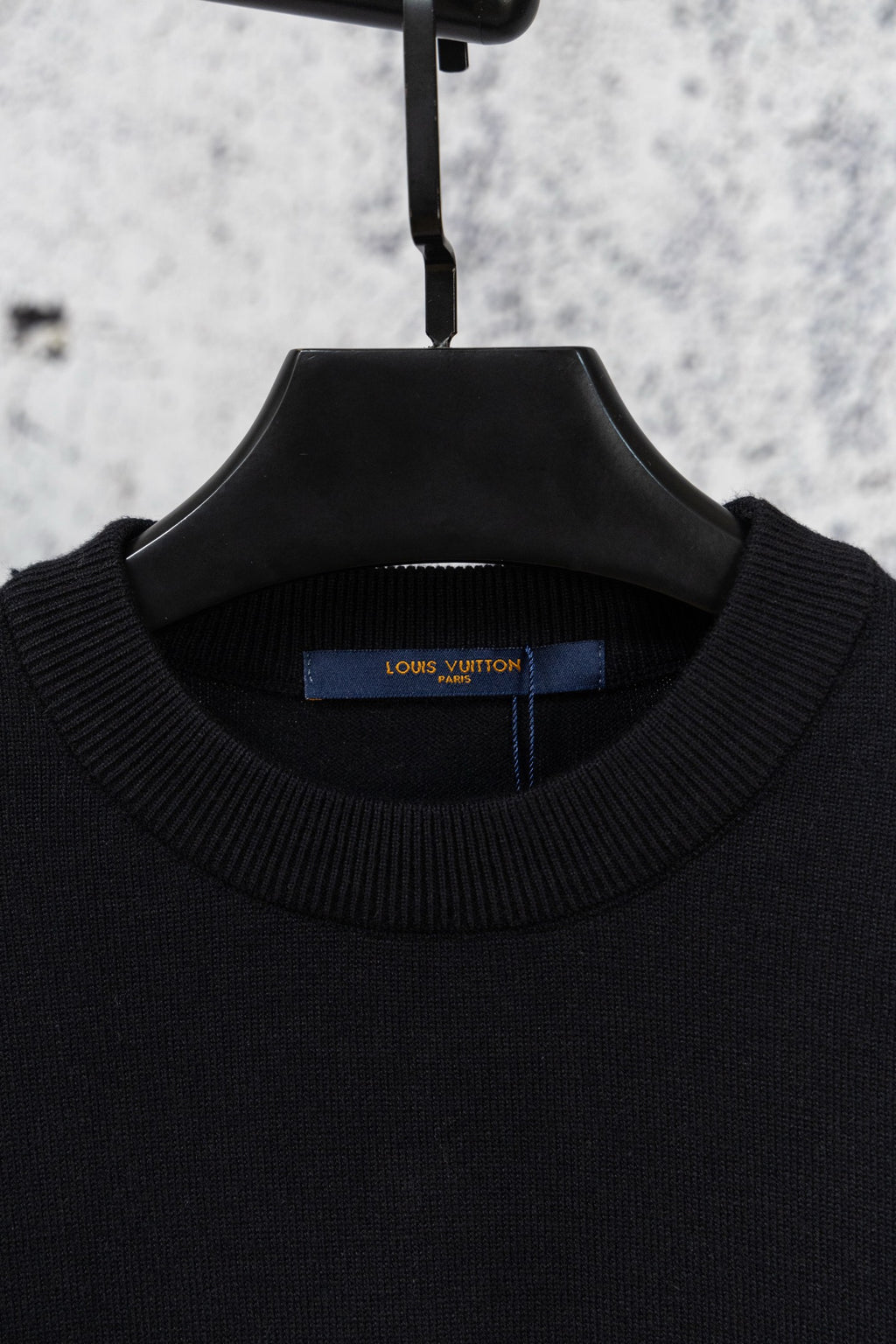 Black crew neck knit sweater on hanger with ribbed collar
