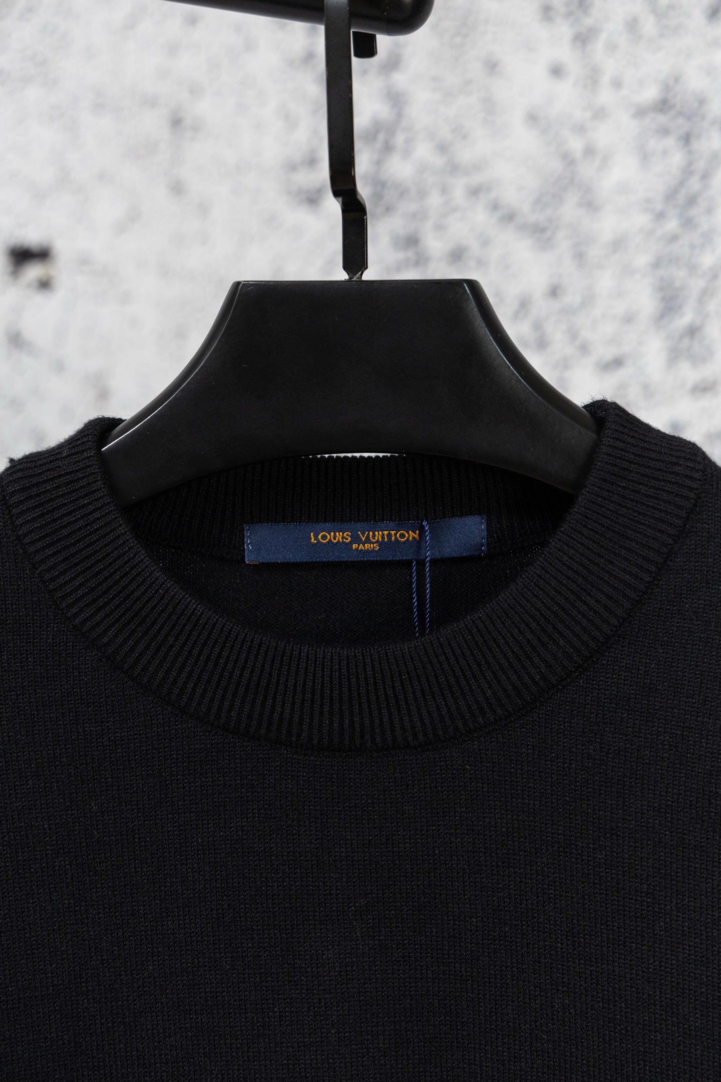 Black crew neck knit sweater on hanger with ribbed collar