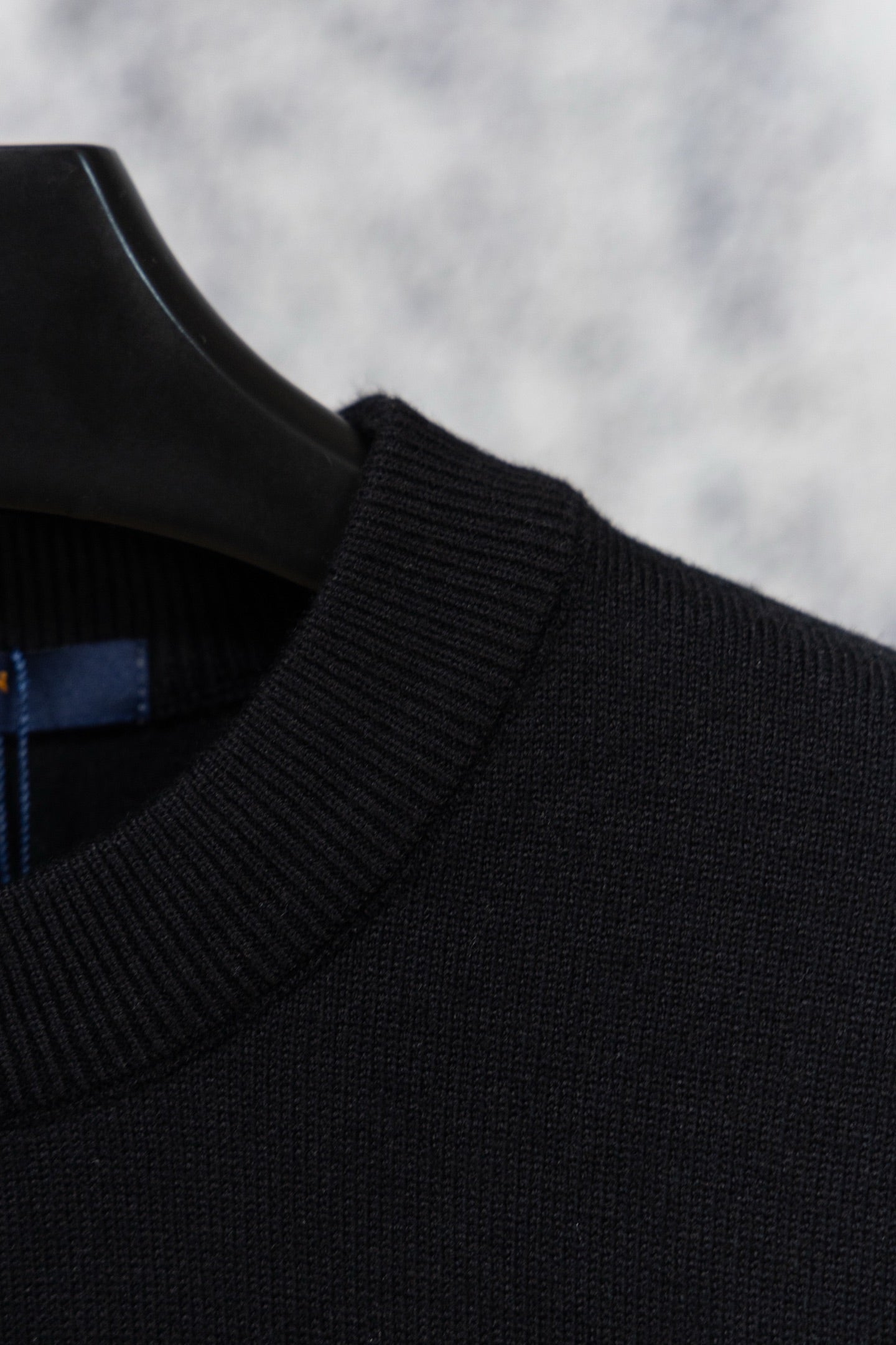 Black knit sweater shoulder and neckline with ribbed collar detail