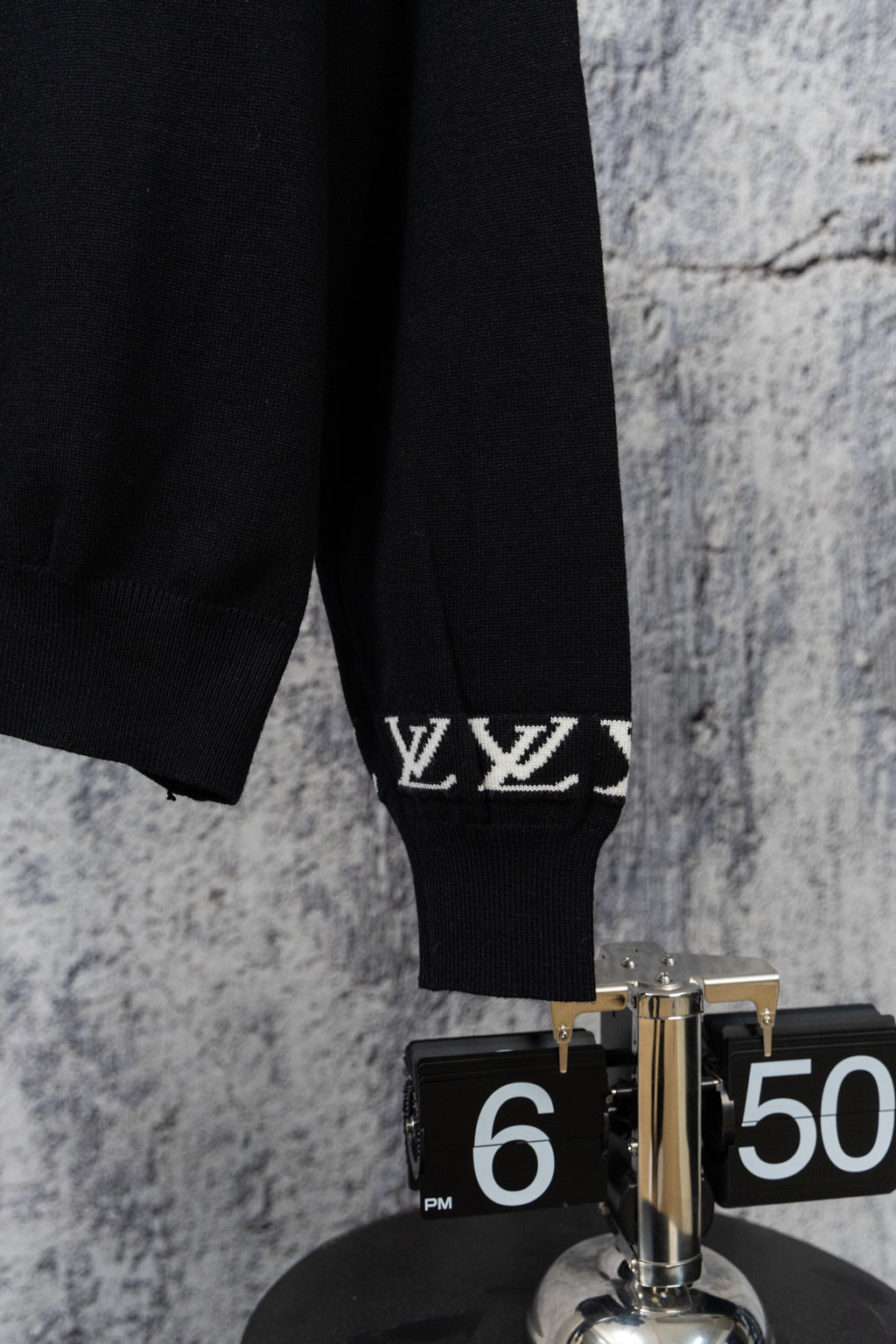 Black sweater sleeve with ribbed cuff and white LV monogram trim