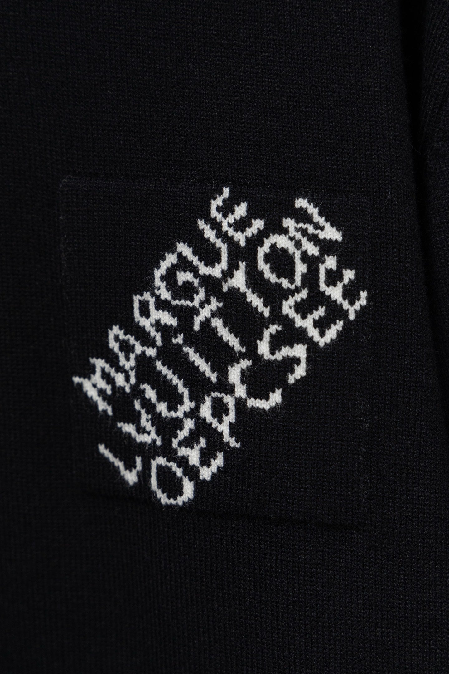 Black knit sweater fabric with white embroidered logo pattern