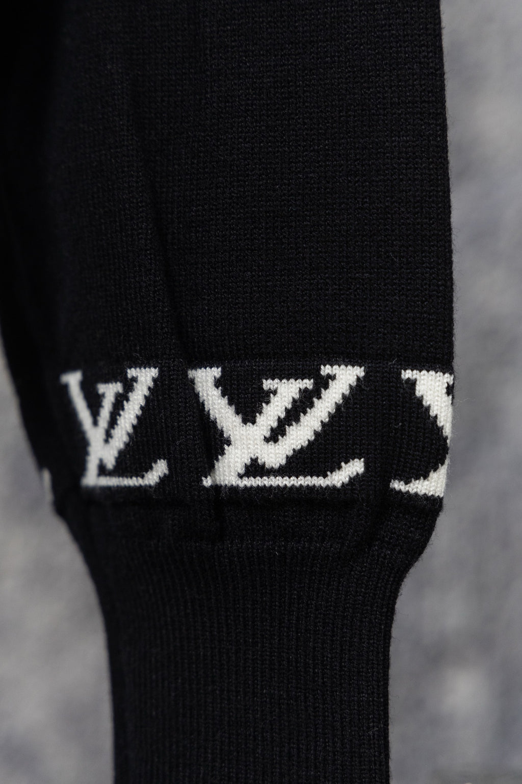 Black ribbed sweater cuff with repeating white LV monogram pattern