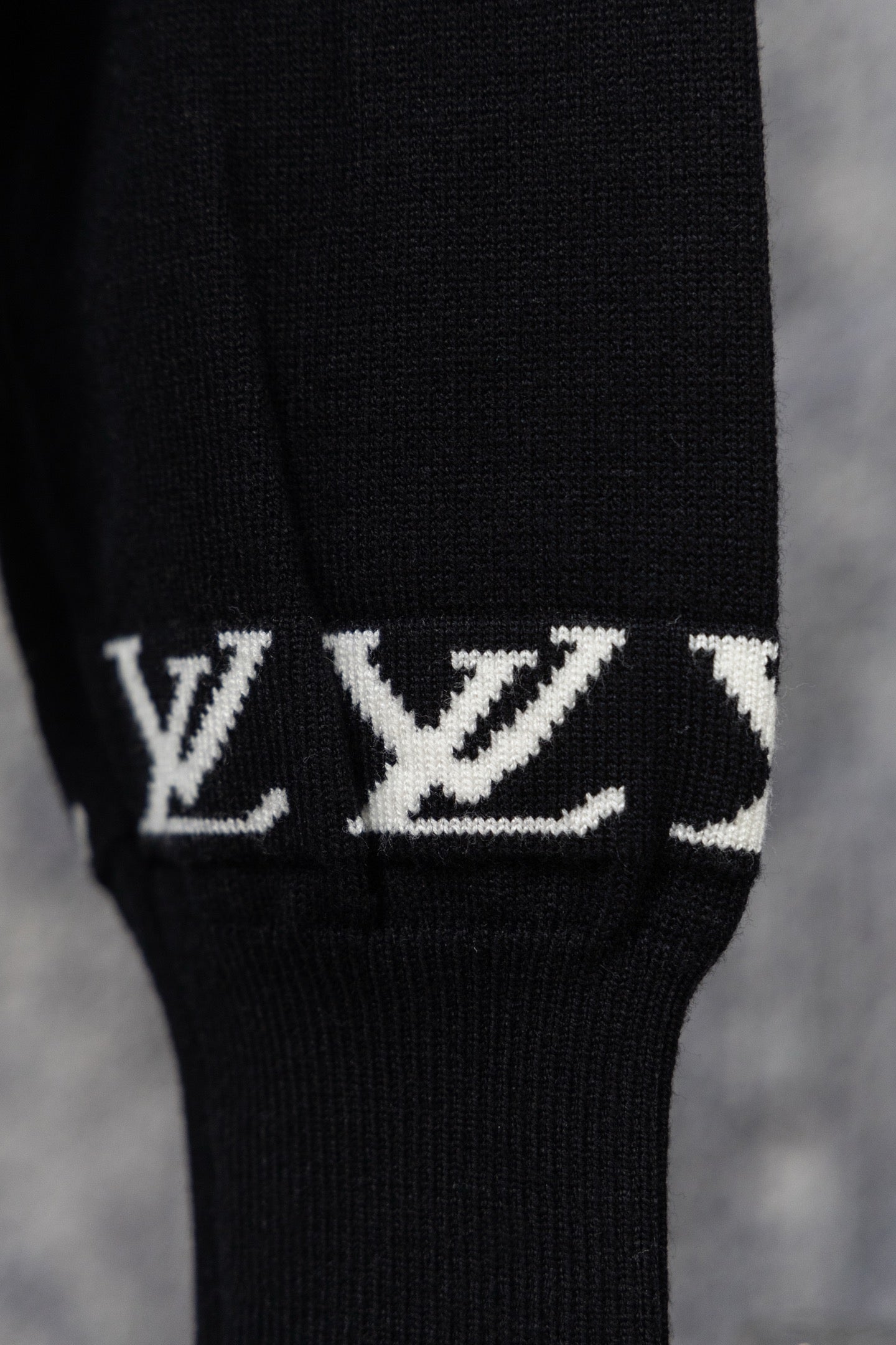 Black ribbed sweater cuff with repeating white LV monogram pattern