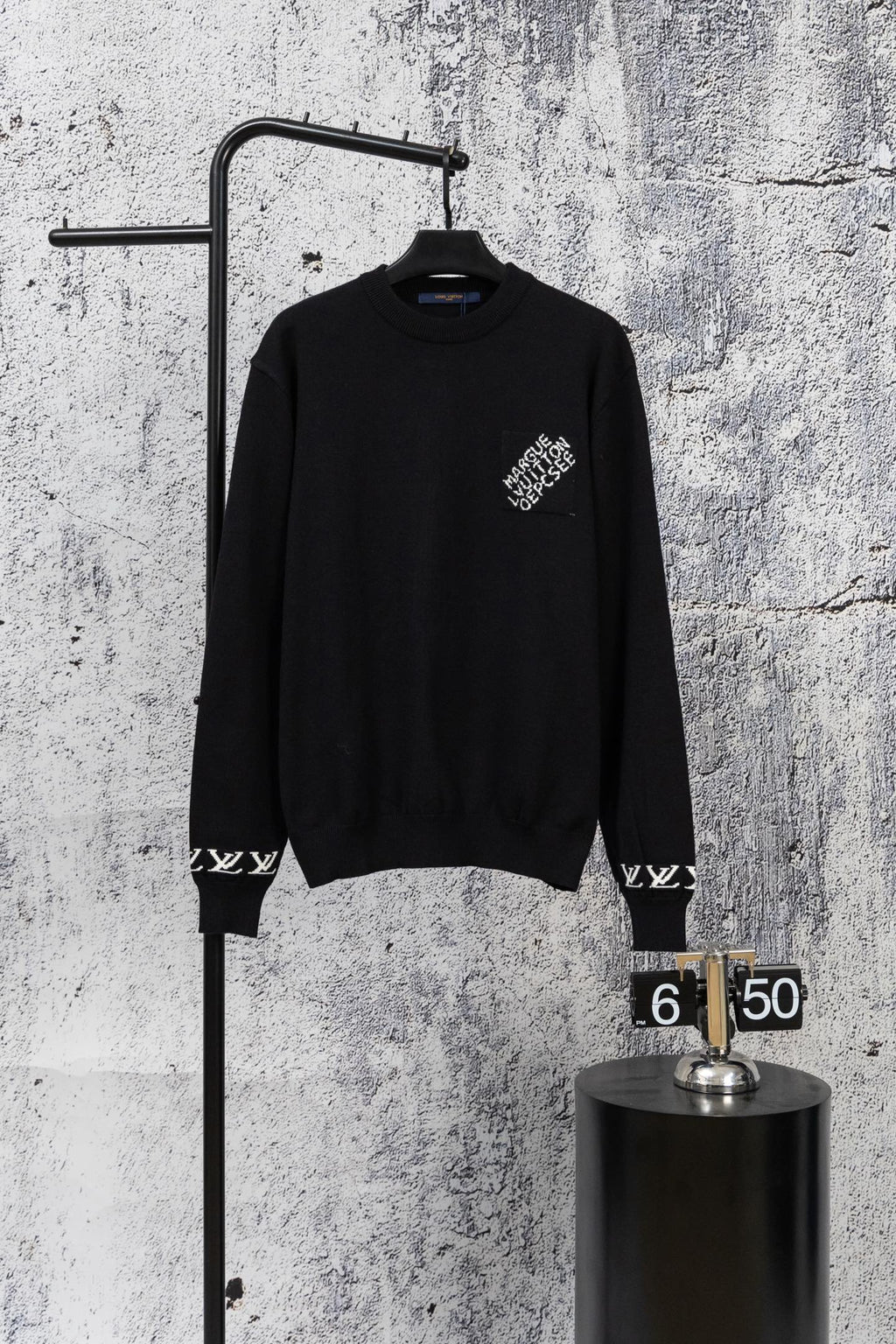 Black knit sweater with crew neck and small white logo detail at chest