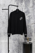 Black knit sweater with crew neck and small white logo detail at chest