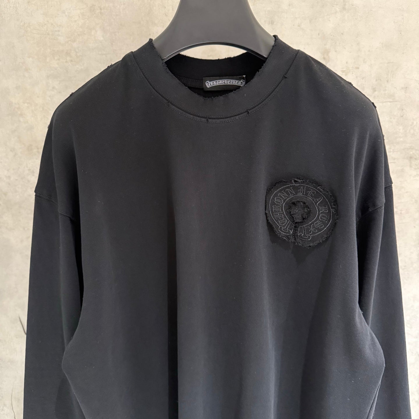 Black long-sleeve crewneck shirt with embroidered chest crest patch