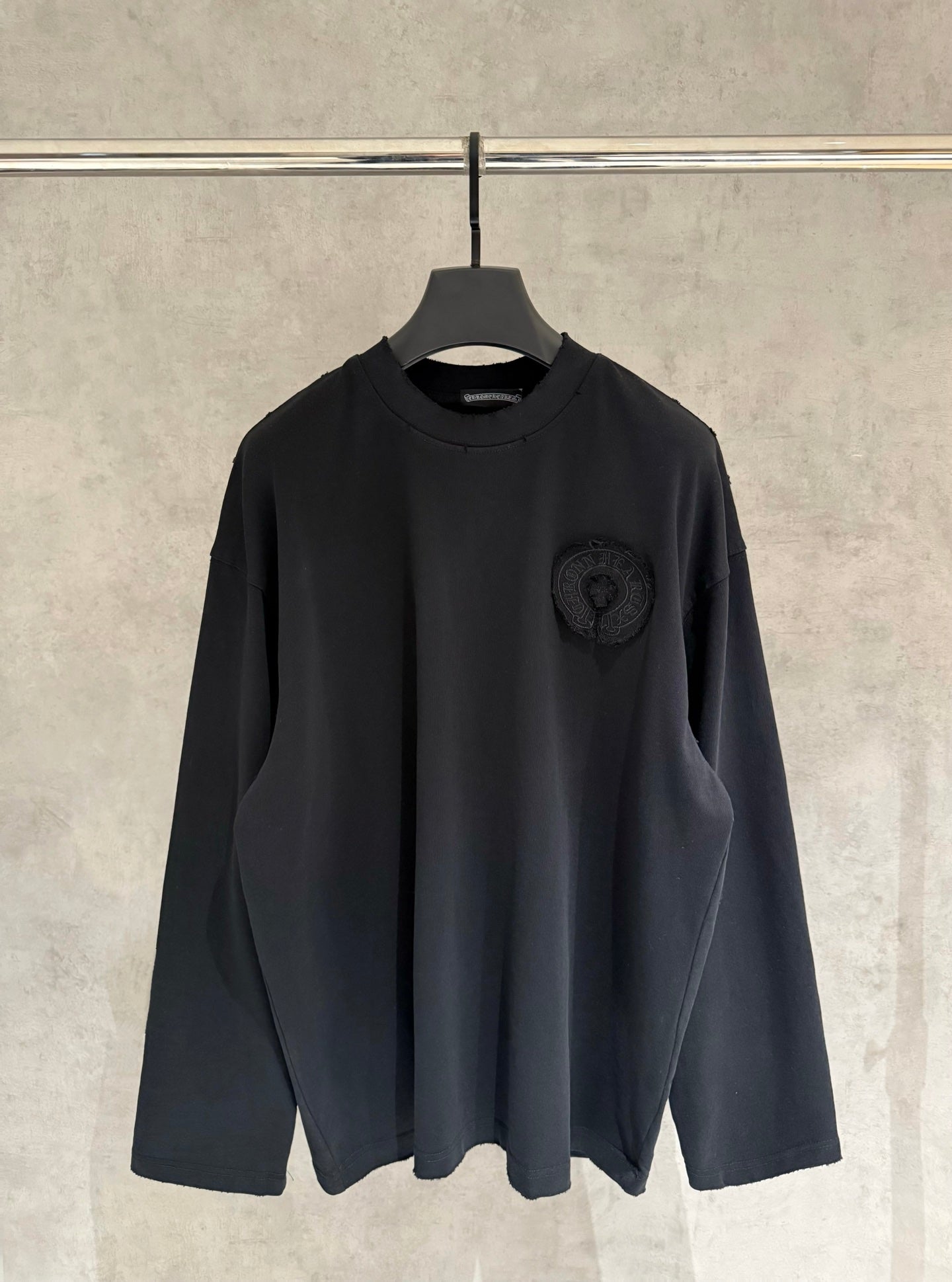Black long-sleeve crewneck shirt with small chest logo patch