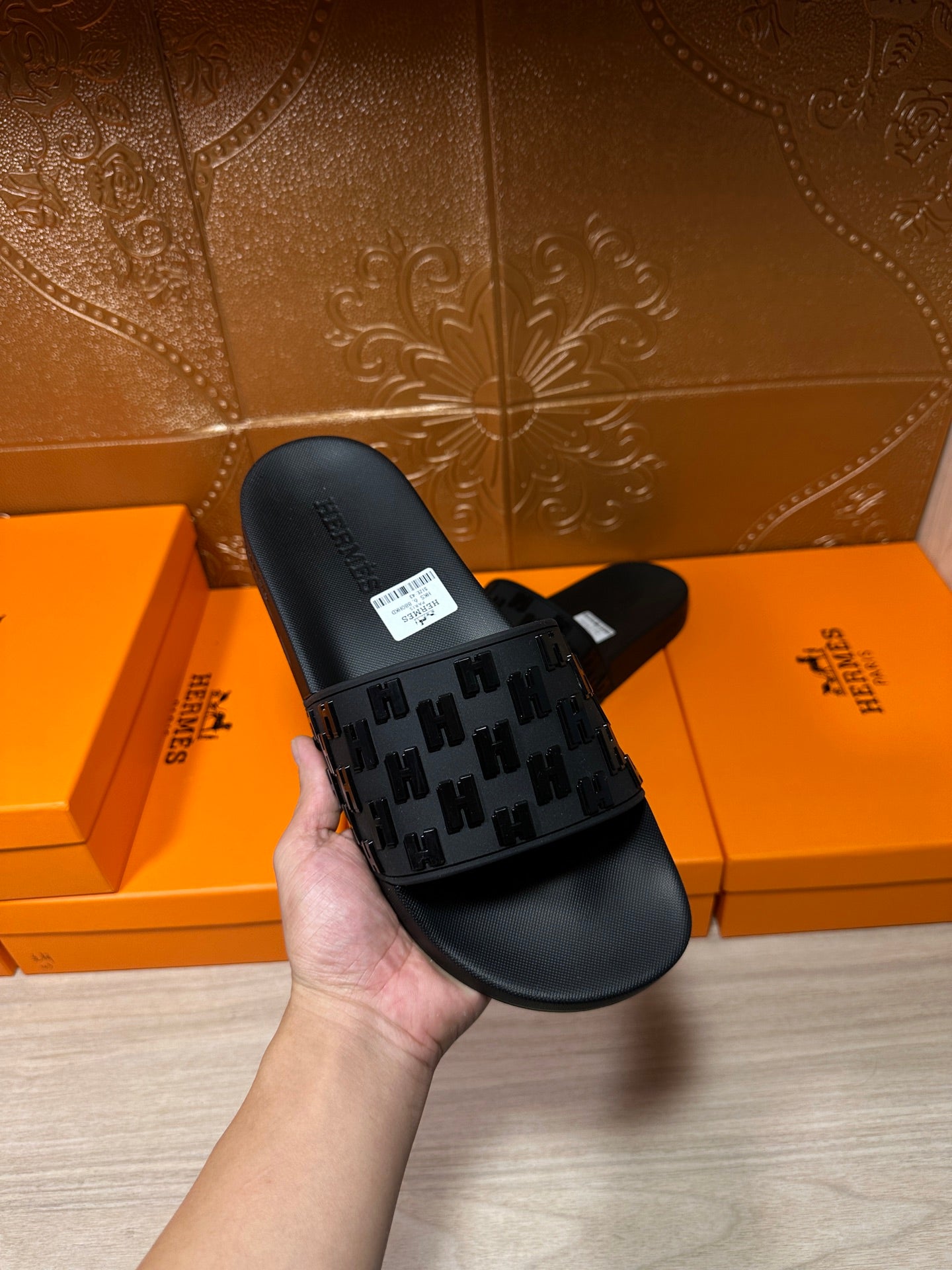 Hermes black slide sandal held in hand, patterned strap and size label