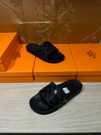 Hermes black slide sandals with angled view of patterned upper strap