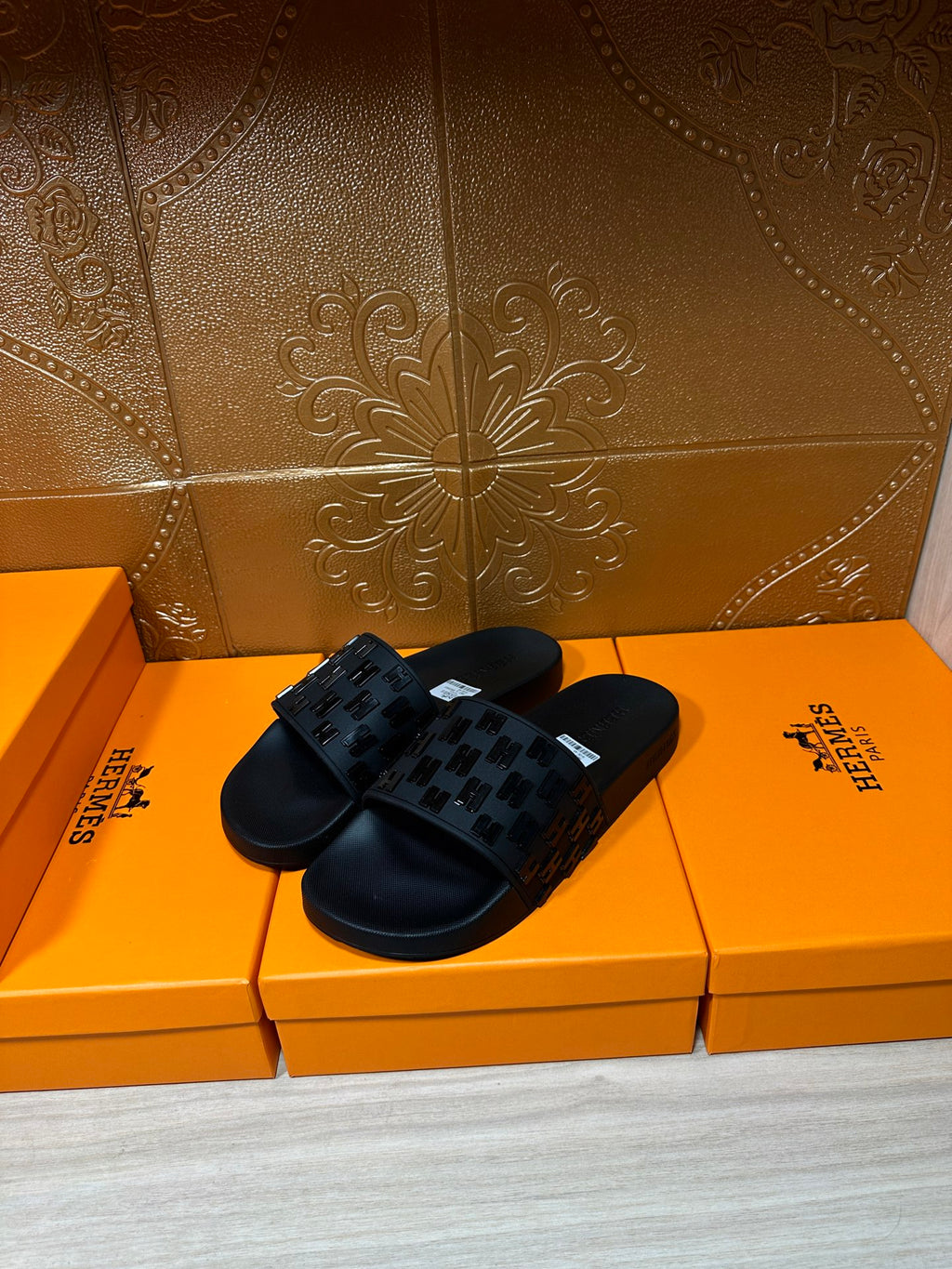 Hermes black slide sandals with textured strap pattern and white label