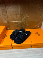 Hermes black slide sandals with textured strap pattern and white label