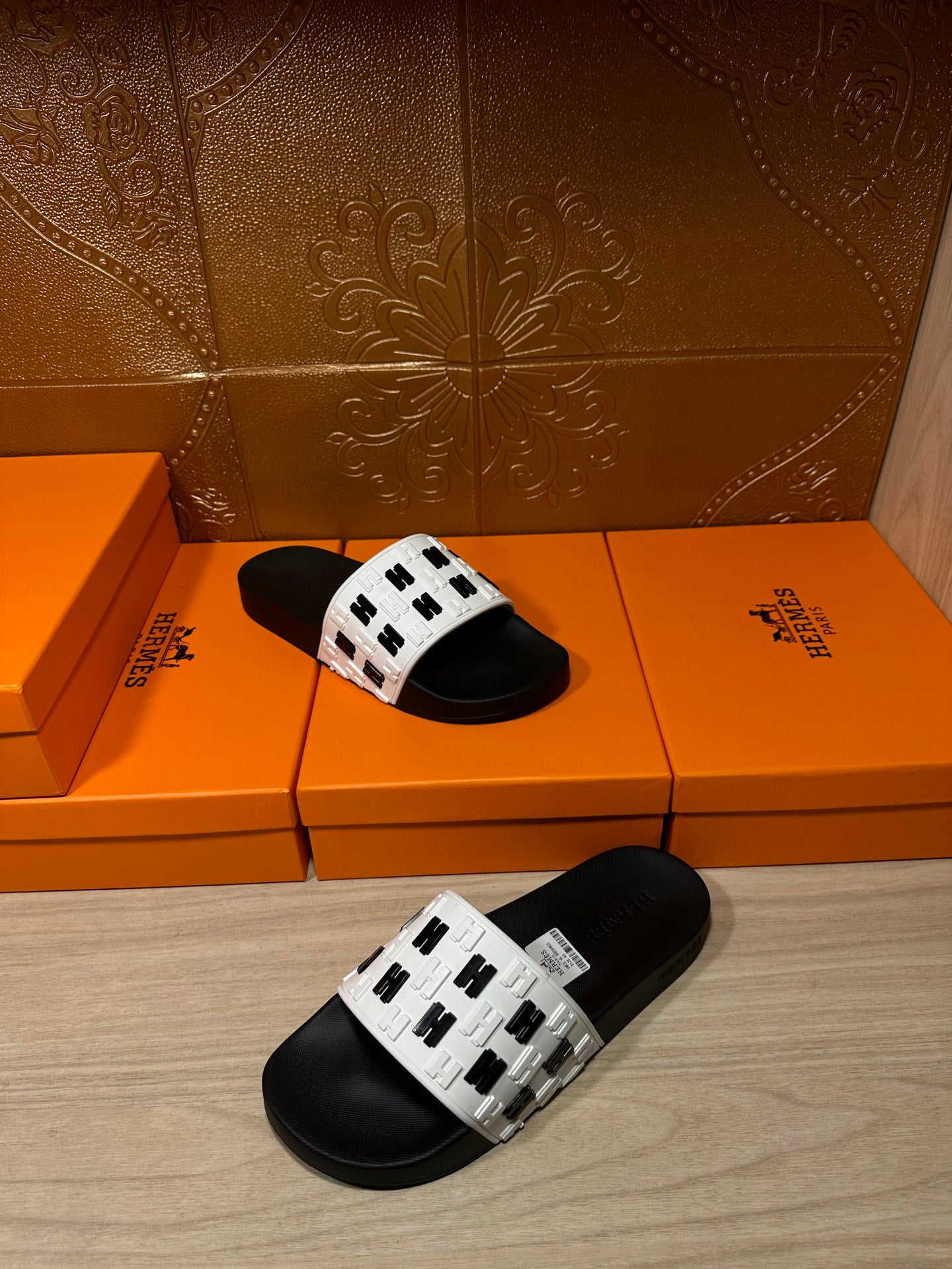 Black slide sandals with white logo-print straps, shown at an angled front view