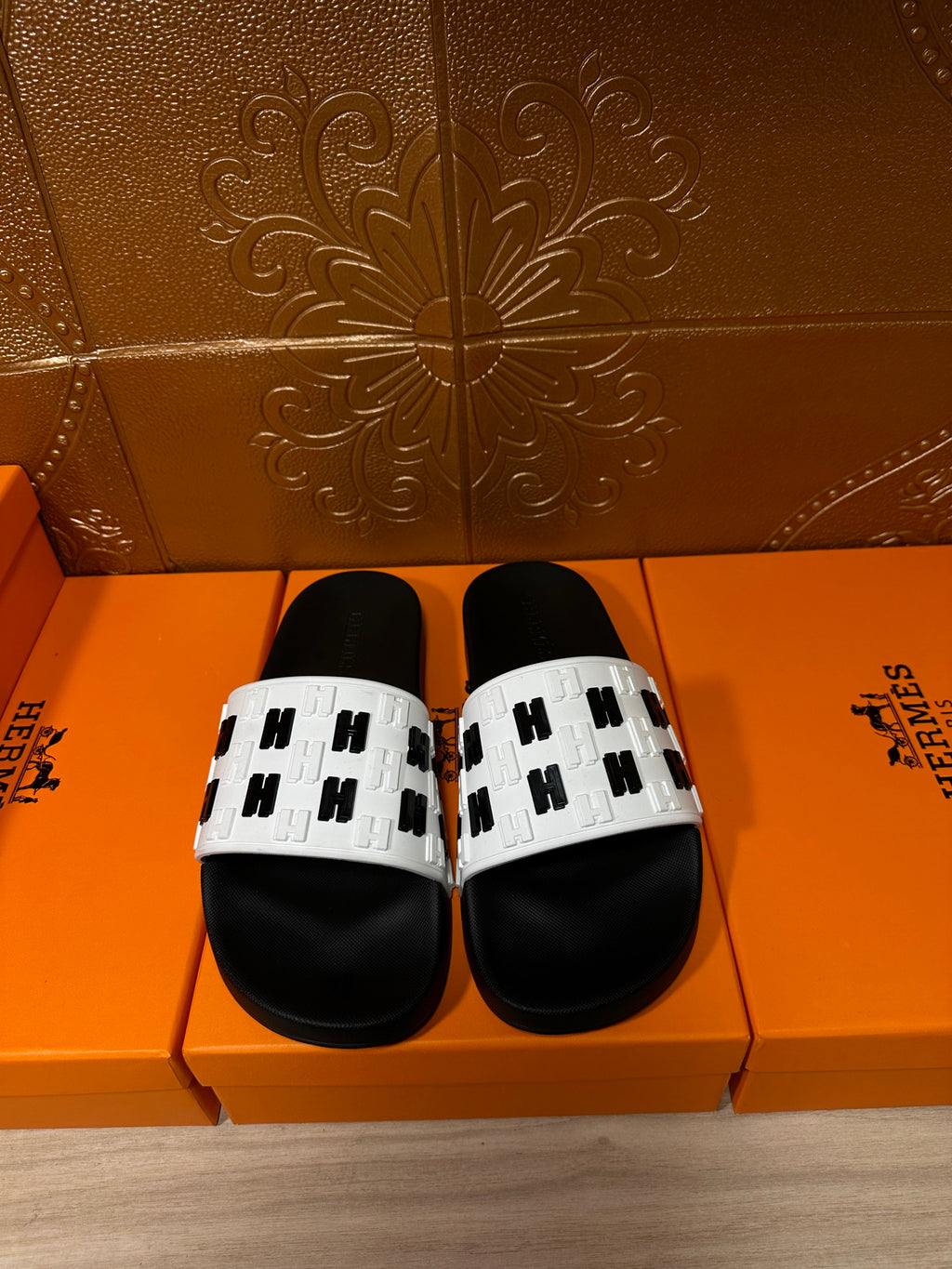 Pair of black slide sandals with white logo-print straps and black footbeds