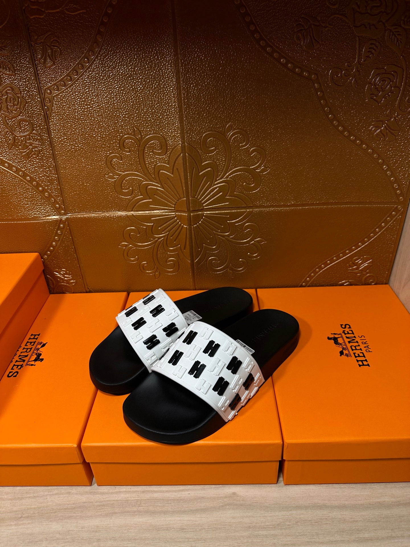 Black slide sandals with white patterned straps and adjustable buckle detail