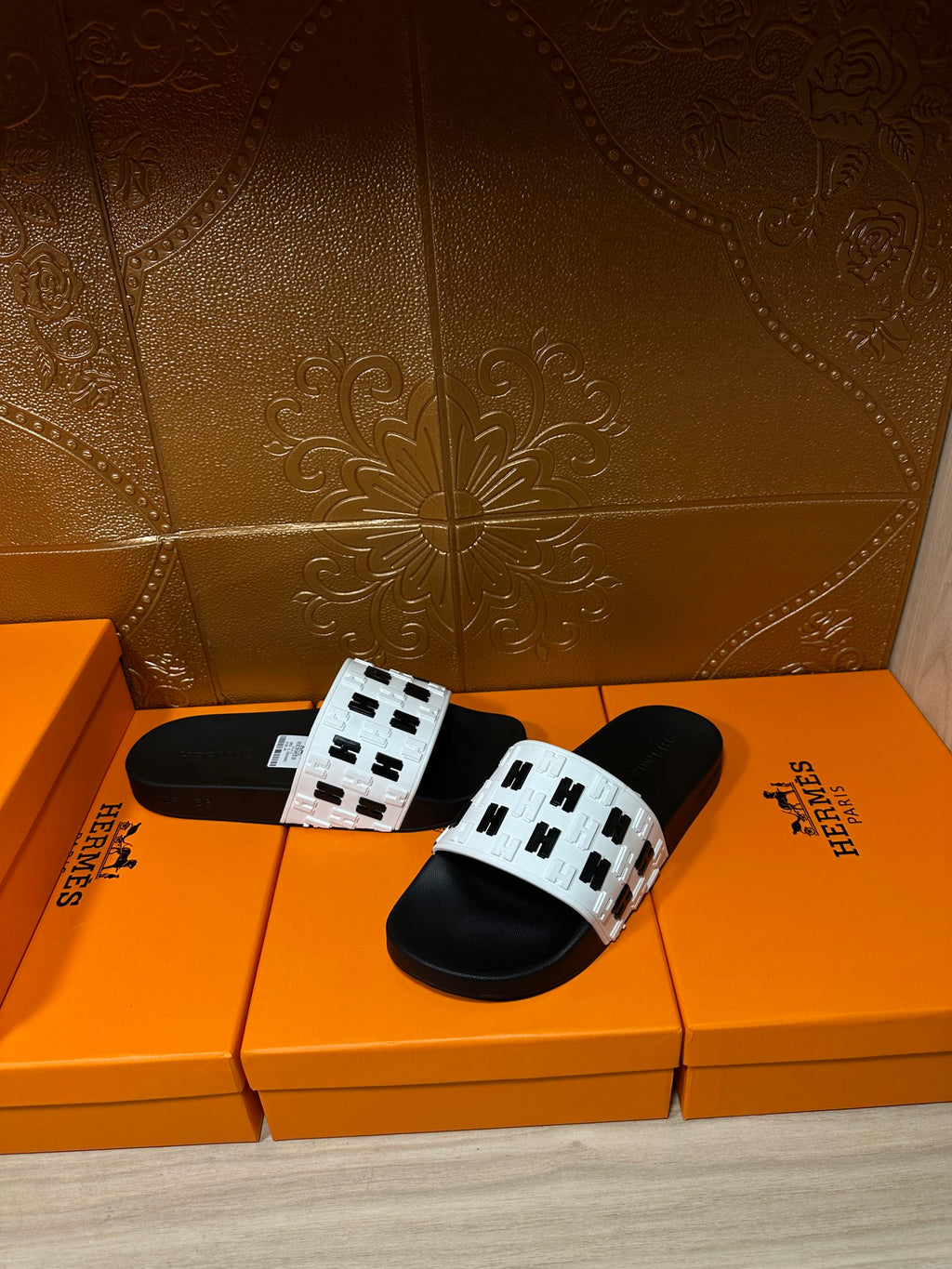 Black slide sandals with white logo-print straps and black footbeds on boxes