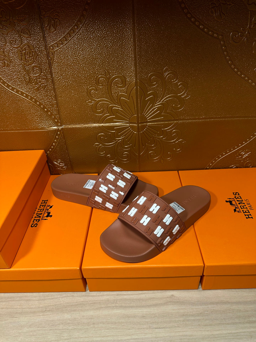 Hermes dark brown slide sandals with H logo strap and rectangular label patch