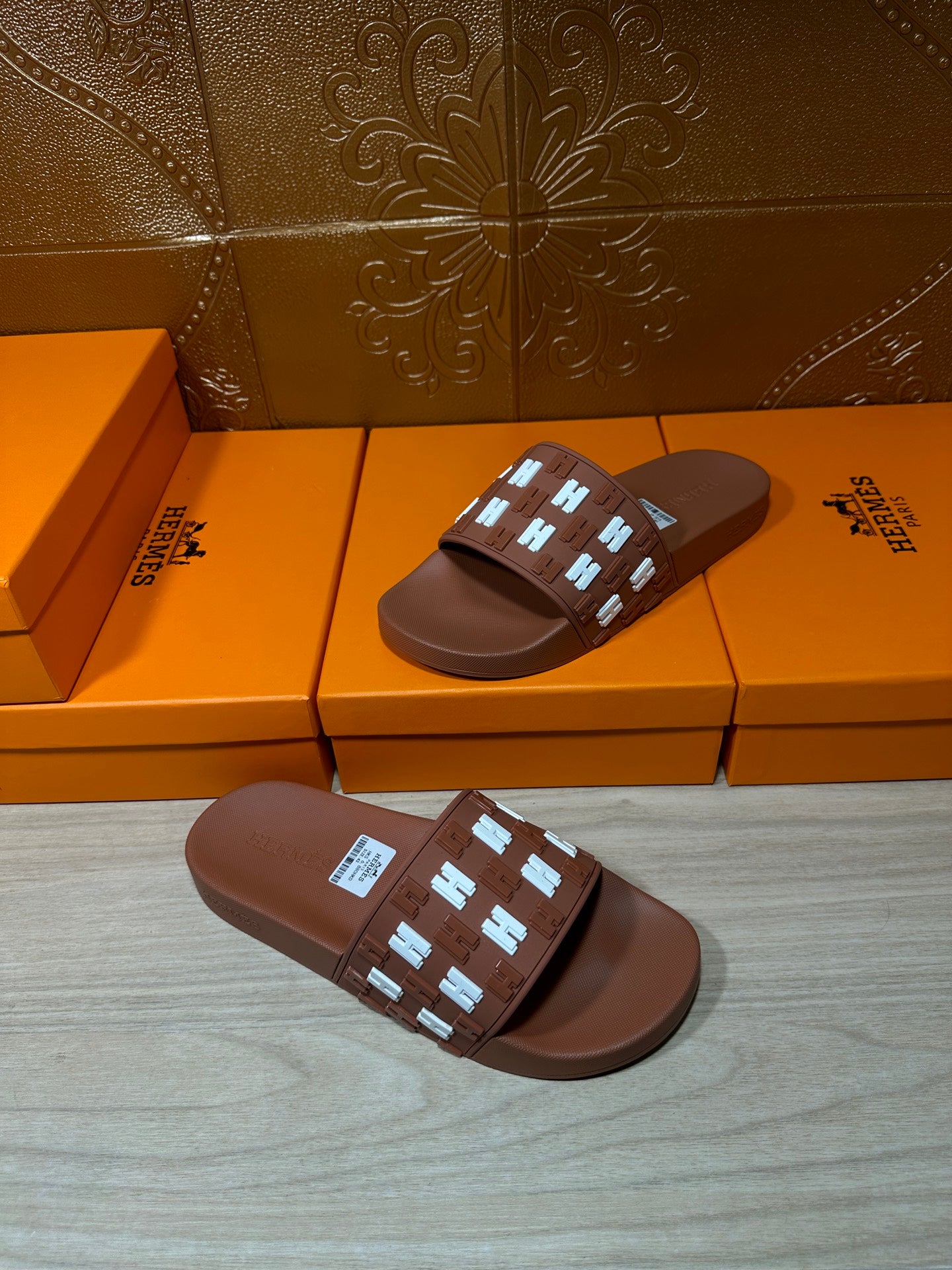 Hermes dark brown slide sandals with patterned H emblem strap and wide cushioned sole