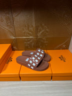 Hermes dark brown slide sandals showing the top strap with H-style logo details