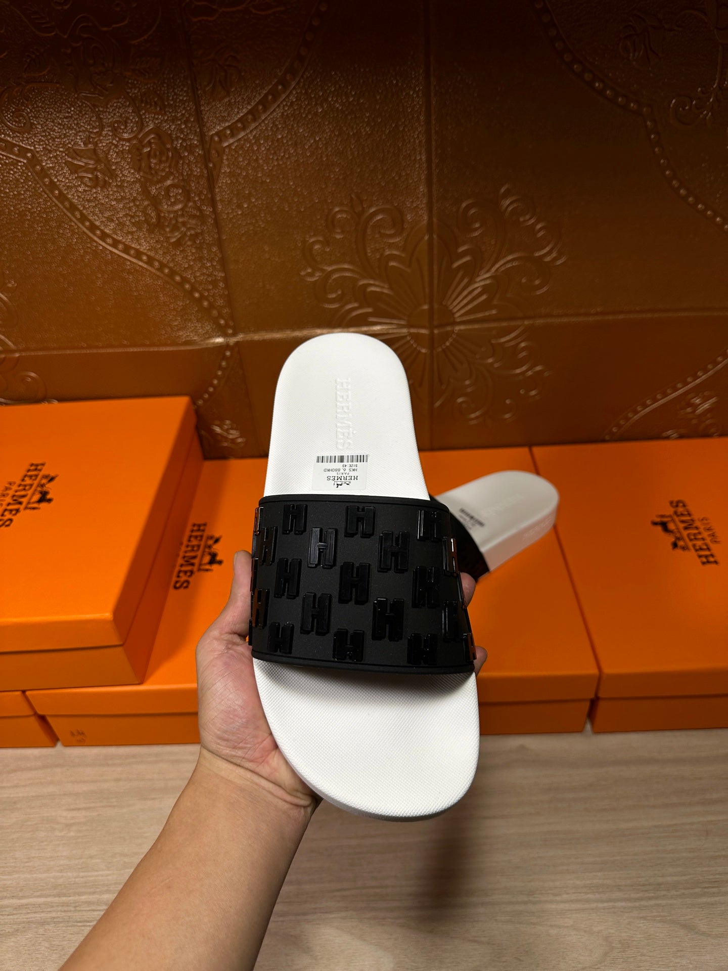 Hermes slide sandals held up, white footbed and black patterned strap
